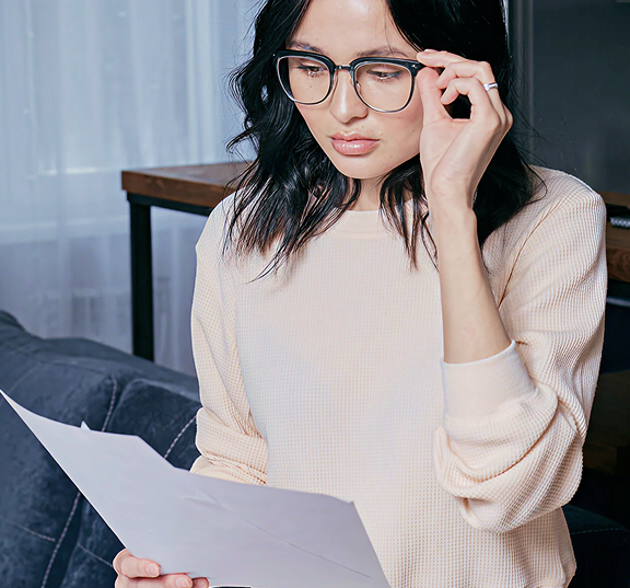 Adult wearing reading glasses. Holding 2 pieces of paper